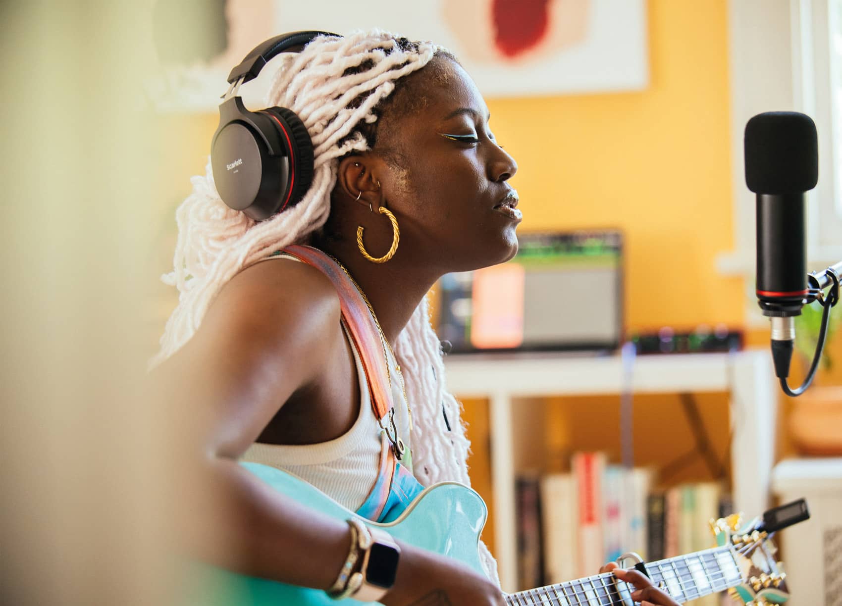 Image of woman singing into microphone and playing guitar